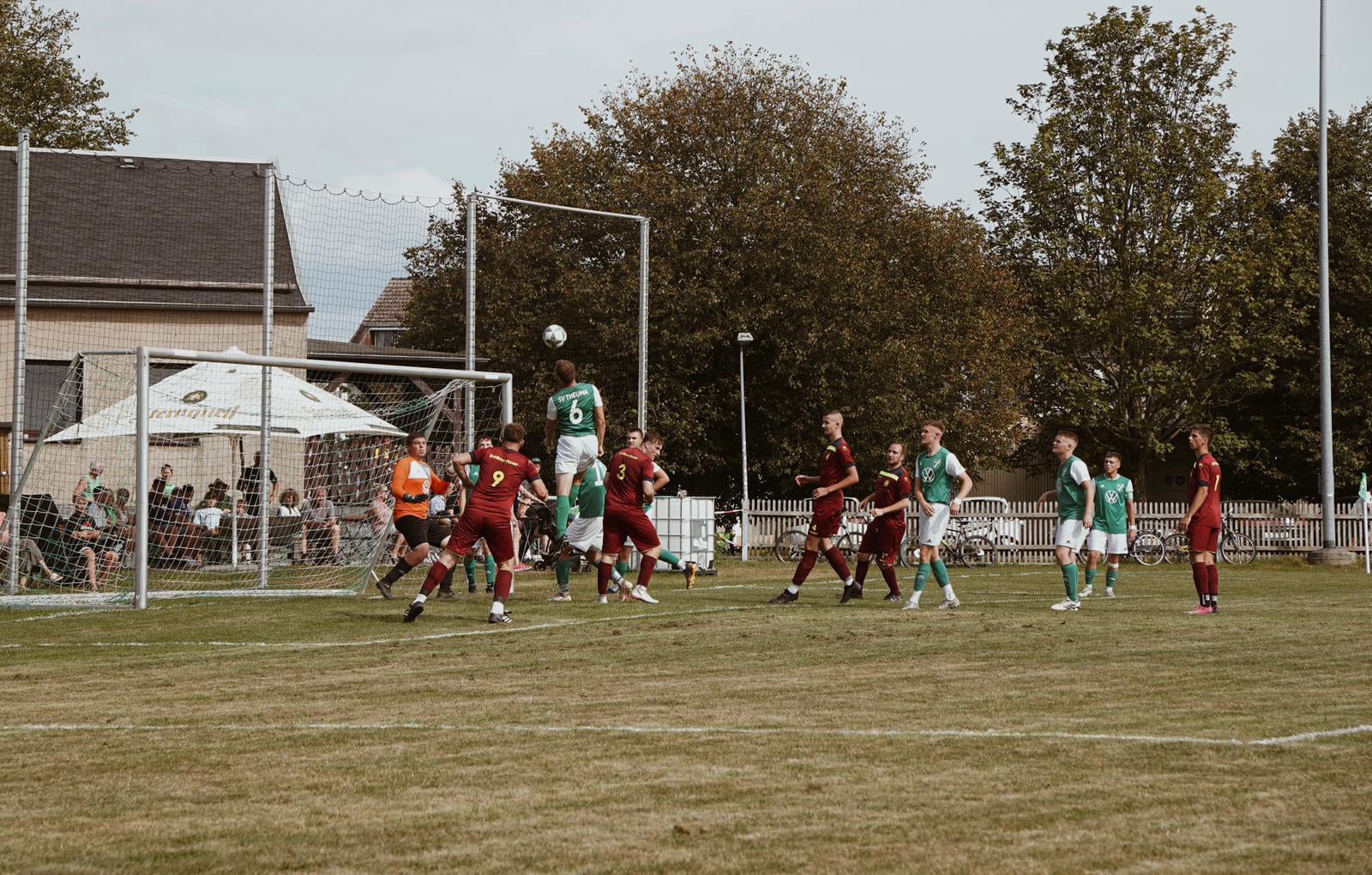 Ein laufendes Fußballspiel, ein Fußballer macht gerade Kopfball in Richtung eines Tors